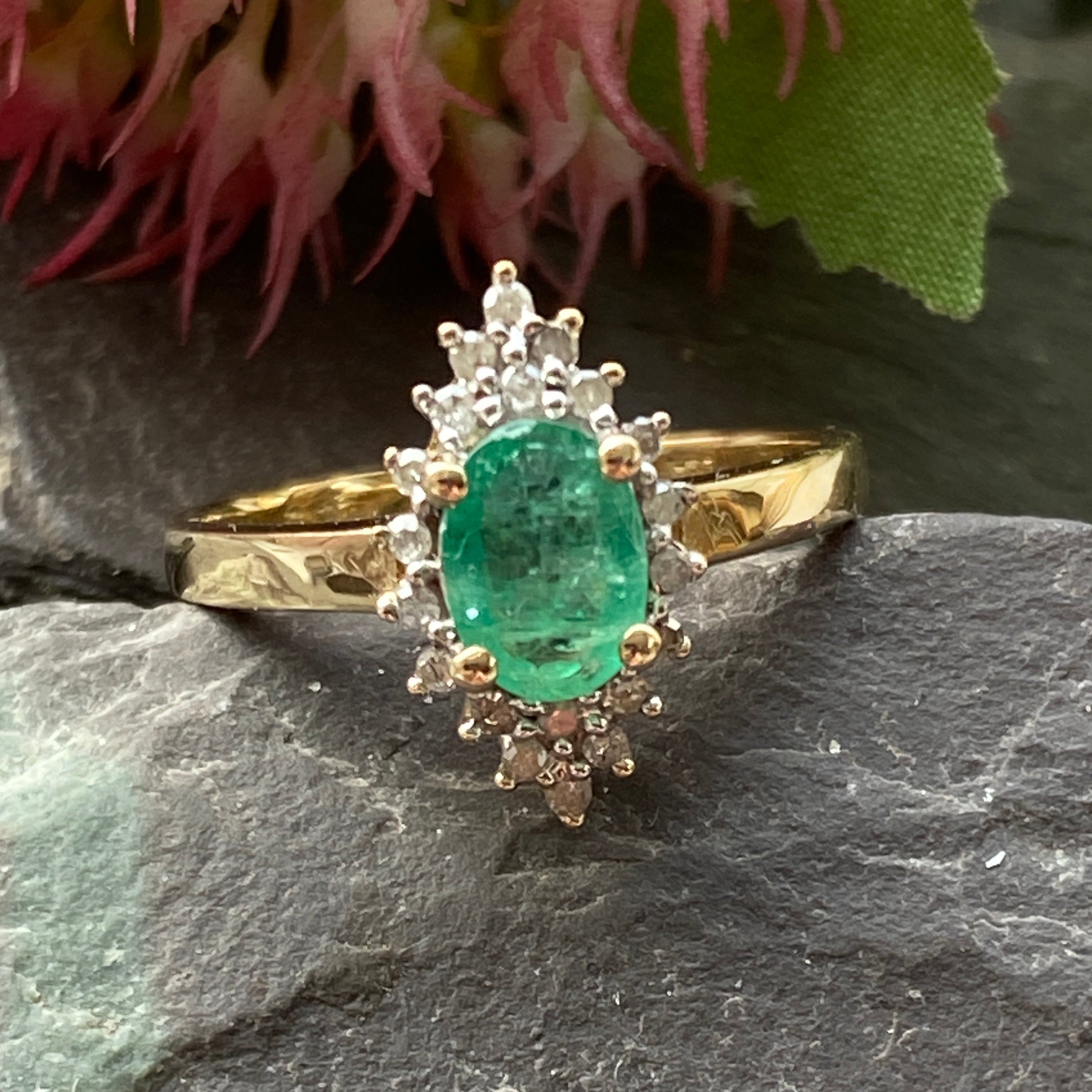 Gold ring with a green gemstone on a dark stone surface