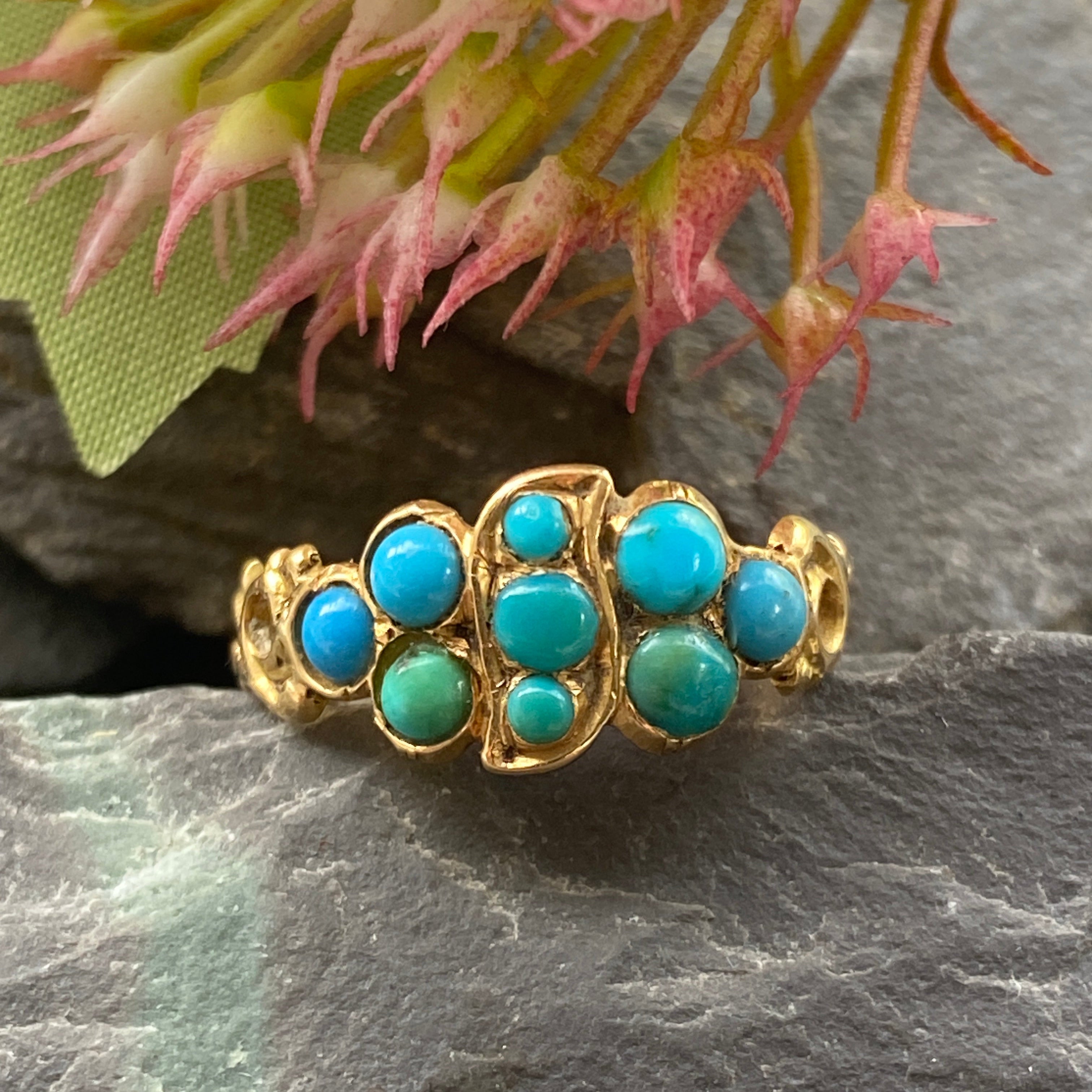 Gold ring with turquoise stones on a dark stone background