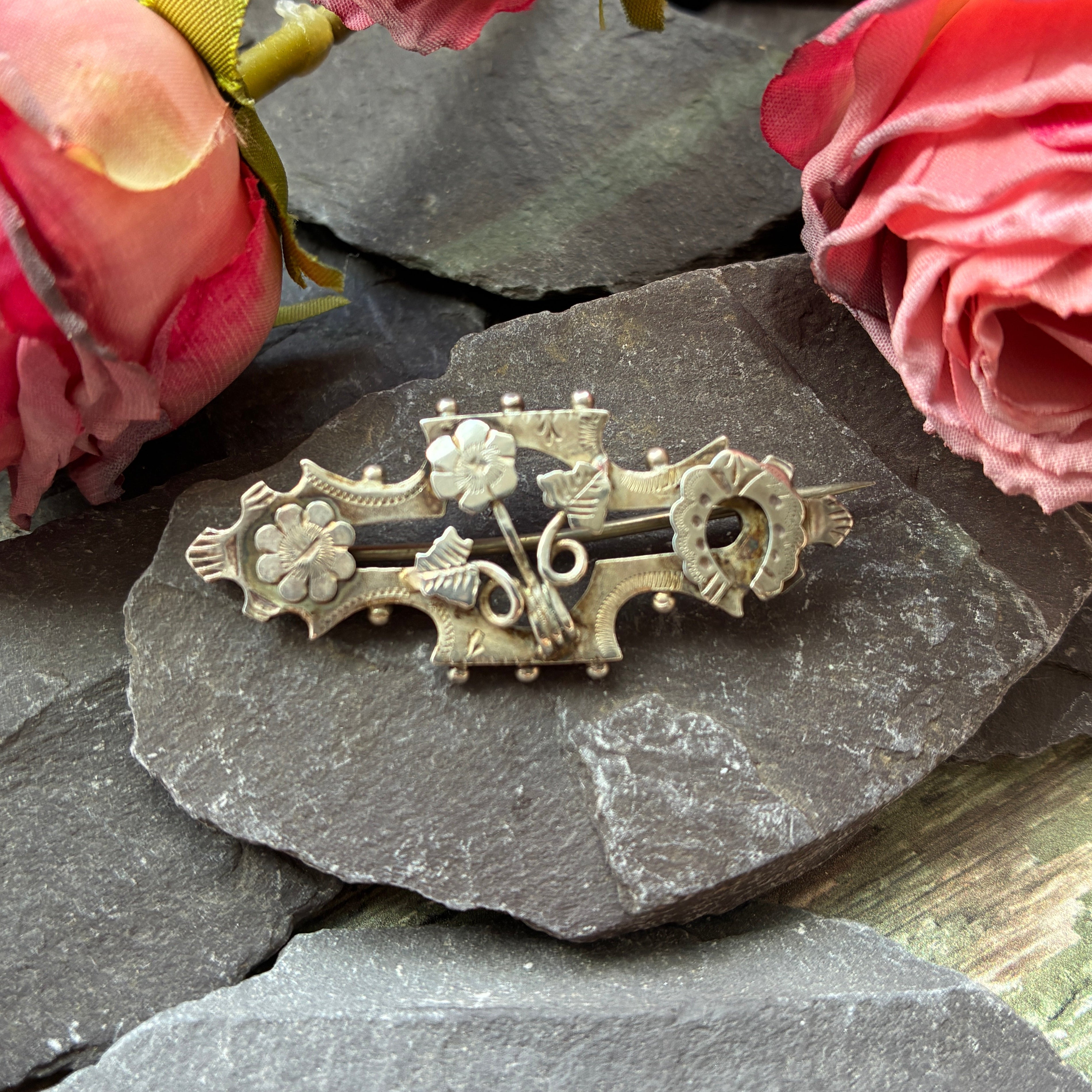 Victorian sterling silver brooch with flowers and horseshoe design.