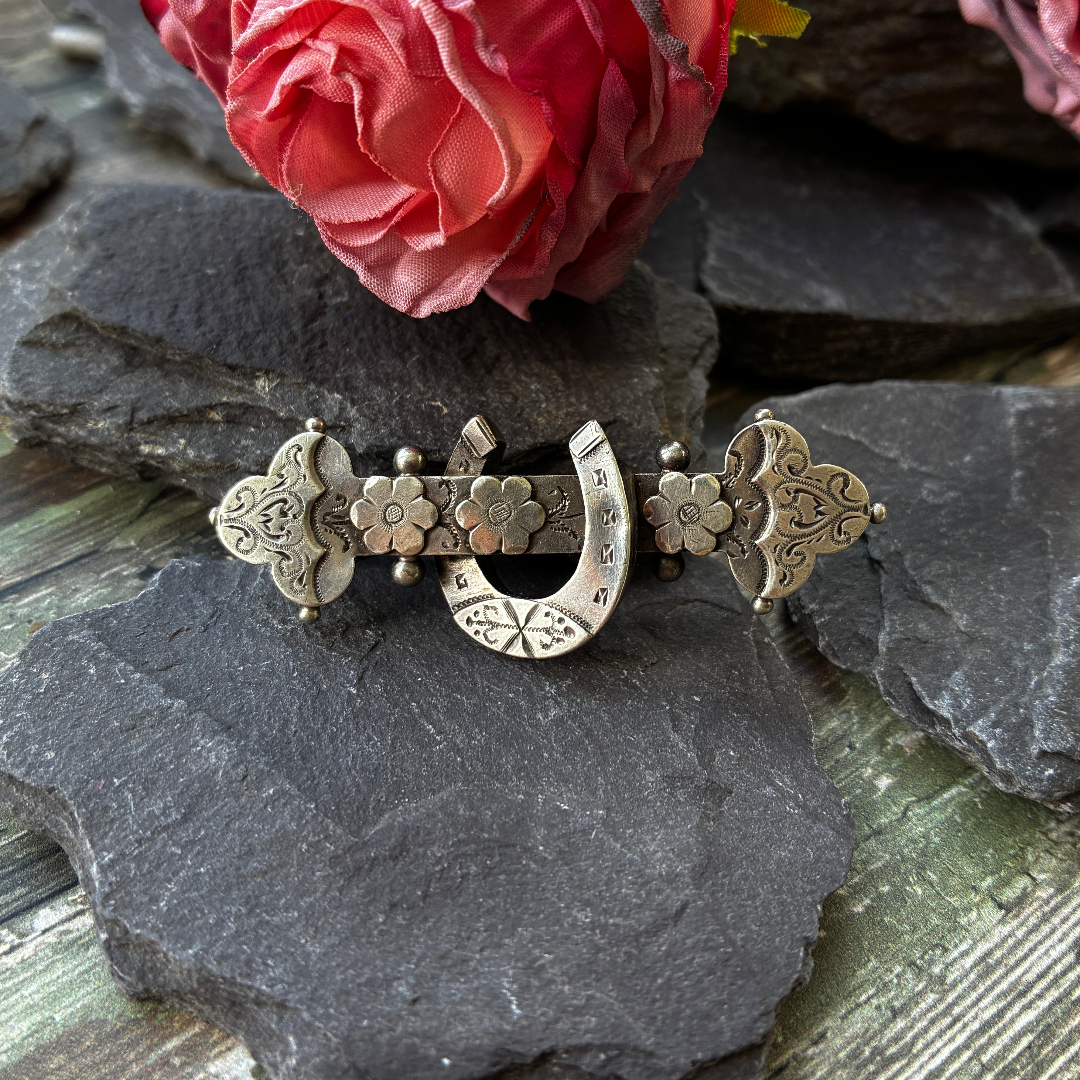 Antique sterling silver sentimental brooch with horseshoe and flowers.