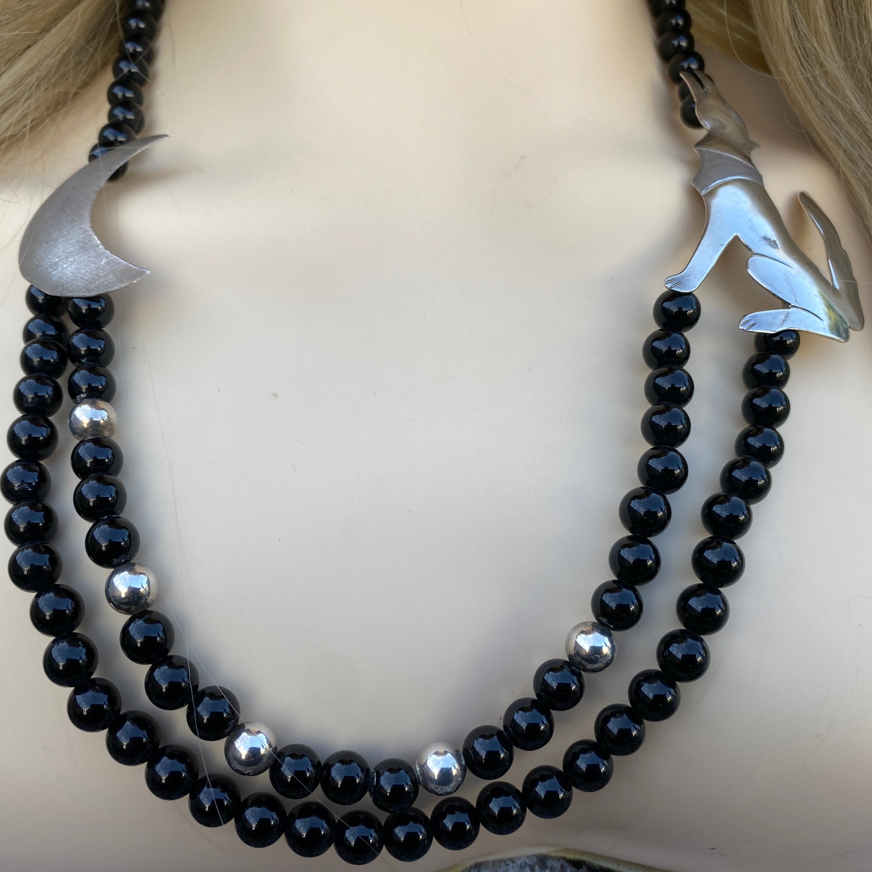 Black beaded necklace with silver accents on a mannequin